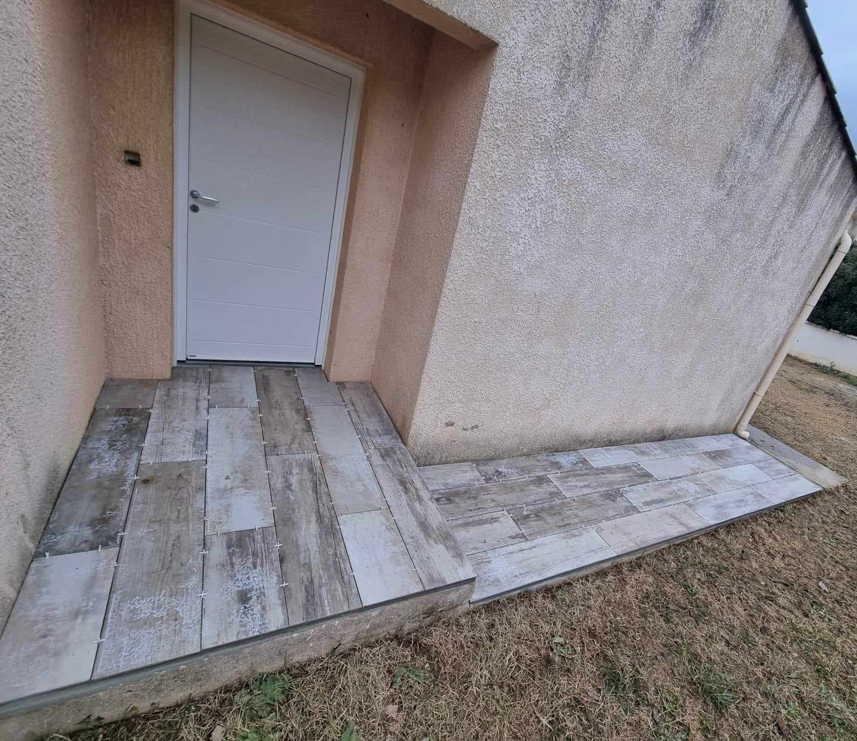 Entrée de maison et bande de propreté carrelées en grès cérame imitation bois vieilli